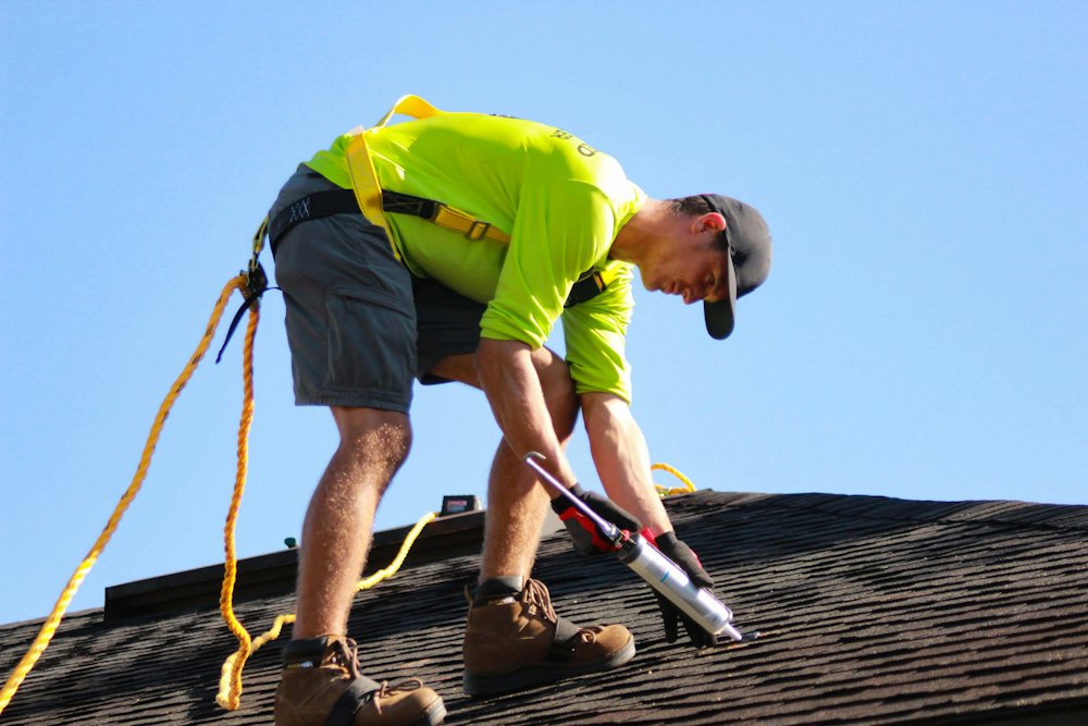 Roofer fastening shingles with a drill